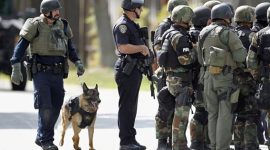 Police officers and a police dog prepare to search a suburban street during a manhunt in Sunnyvale, California, October 5, 2011.  A disgruntled worker, identified as Shareef Allman, opened fire on Wednesday at a Northern California cement plant and quarry, killing two people and injuring six, police said. Allman was also suspected of shooting a woman contract worker for Hewlett Packard during an attempted carjacking a short time later, Santa Clara County Sheriff's spokesman Sgt. Jose Cardoza said. REUTERS/Beck Diefenbach (UNITED STATES - Tags: CRIME LAW ANIMALS) - RTR2S9HP