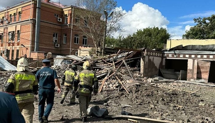 Warga berjalan melewati lokasi ledakan dengan petugas pemadam kebakaran di Taganrog, wilayah Rostov, Rusia, Jumat (28/7/2023). (Foto: thenews/Twitter/@DD_Geopolitics)