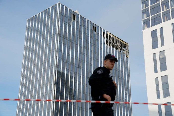 Seorang anggota dinas keamanan berjaga di samping lokasi bangunan yang rusak akibat serangan drone Ukraina di Moskow, Rusia, Senin (24/7/2023) waktu setempat.(Foto: REUTERS/Maxim Shemetov)
