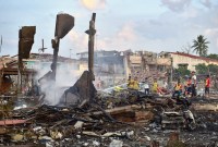Petugas pemadam kebakaran Thailand memadamkan bara api di sekitar rumah yang hancur setelah ledakan merobek gudang kembang api, menewaskan duabelas orang dan melukai lebih dari 121 orang, di distrik Sungai Kolok di provinsi Narathiwat, Thailand selatan Sabtu (29/7/2023). (Foto: AFP/Madaree T)