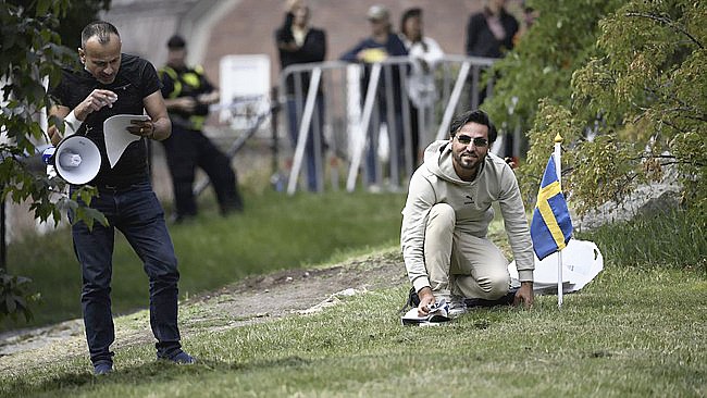 Salwan Momika dan Salwan Najem kembali menggelar aksi membakar Al Quran di luar gedung parlemen Swedia di Stockholm pada Senin (31/7) siang. (Foto: AFP/JONATHAN NACKSTRAND)