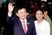 Thaksin Shinawatra bersama putrinya Paetongtarn Shinawatra saat dia tiba di Bangkok. (Wason Wanichakorn/AP)