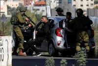 Tentara Israel menahan warga Palestina setelah menghentikan mobil mereka di dekat pos pemeriksaan Huwara, pintu masuk selatan kota Nablus, di Tepi Barat yang diduduki, Jumat (20/10/2023). (AFP/Zain JAAFAR)