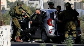 Tentara Israel menahan warga Palestina setelah menghentikan mobil mereka di dekat pos pemeriksaan Huwara, pintu masuk selatan kota Nablus, di Tepi Barat yang diduduki, Jumat (20/10/2023). (AFP/Zain JAAFAR)