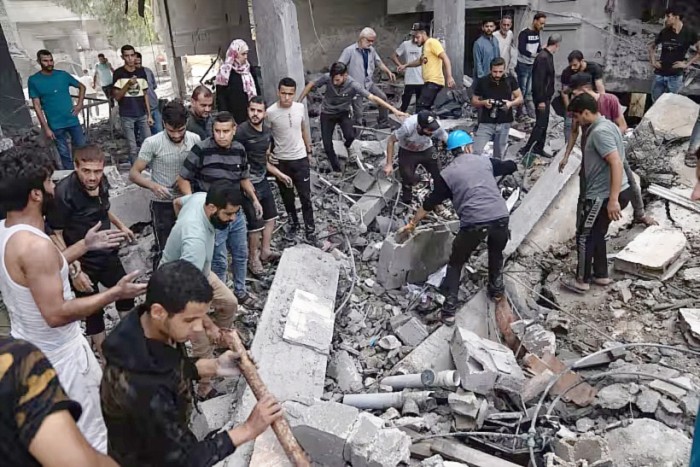 Warga Palestina mencari korban selamat di sebuah bangunan yang hancur akibat pemboman Israel di kamp pengungsi Rafah di Jalur Gaza, Selasa (17/10/2023). (AP Photo/Fatima Shbair)