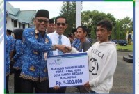 Sekda Tanahlaut, Dahnial Kipli , didampingi Iwan, Kepala kantor Cabang Bank Kalsel Pelaihari, menyerahkan bantuan secara simbolis kepada Hairul Sidik. Repro Humas Tanah Laut.