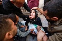 Sejumlah orang dan kerabat mencoba menghibur seorang wanita yang menggendong jenazah bayi perempuannya, Jumat (1/12/2023) di halaman rumah sakit al-Najjar di Rafah, Gaza selatan. (AFP-Getty Images/Mohammed Abed)