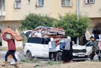 Penduduk kompleks perumahan Kota Hamad yang didanai Qatar di Khan Yunis di Jalur Gaza selatan, membawa beberapa barang milik mereka saat meninggalkan rumah setelah menerima pemberitahuan dari tentara Israel tentang serangan yang akan segera terjadi. (AFP/Mahmud Hams)