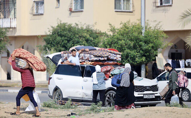 Penduduk kompleks perumahan Kota Hamad yang didanai Qatar di Khan Yunis di Jalur Gaza selatan, membawa beberapa barang milik mereka saat meninggalkan rumah setelah menerima pemberitahuan dari tentara Israel tentang serangan yang akan segera terjadi. (AFP/Mahmud Hams)