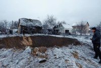 Seorang penduduk setempat berdiri di samping kawah di lokasi serangan rudal Rusia di Kyiv, Ukraina, Senin (11/12/2023). (Foto: Reuters/Valentyn Ogirenko)