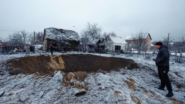 Seorang penduduk setempat berdiri di samping kawah di lokasi serangan rudal Rusia di Kyiv, Ukraina, Senin (11/12/2023). (Foto: Reuters/Valentyn Ogirenko)