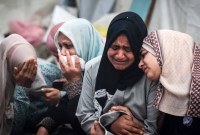 Warga Palestina berduka atas kerabat mereka yang tewas dalam serangan Israel semalam di kamp pengungsi Al-Maghazi. [AFP/Getty Images/Mahmud Hams]