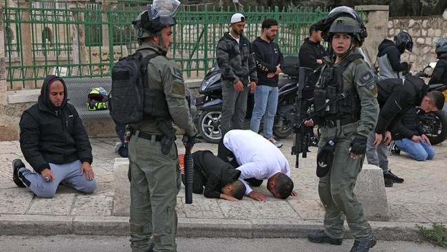 Polisi Israel berjaga-jaga di antara warga Palestina yang beribadah di kompleks Al Aqsa saat hari pertama Ramadan. [AFP/Ahmad Gharabli]