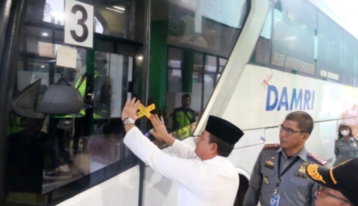 Kepala Kemenkumham Kalsel Taufiqurrakhman menempelkan stiker Immigration Clearance pada bus yang membawa jamaah ke Bandara Syamsudin Noor di Banjarbaru, Minggu (12/5/2024). [ANTARA/Firman]