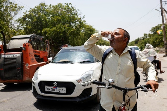 Seorang pria meminum minuman dingin yang ditawarkan oleh penduduk setempat pada hari musim panas saat gelombang panas terjadi di Narela, New Delhi, India, Minggu (2/6/2024). [Reuters]