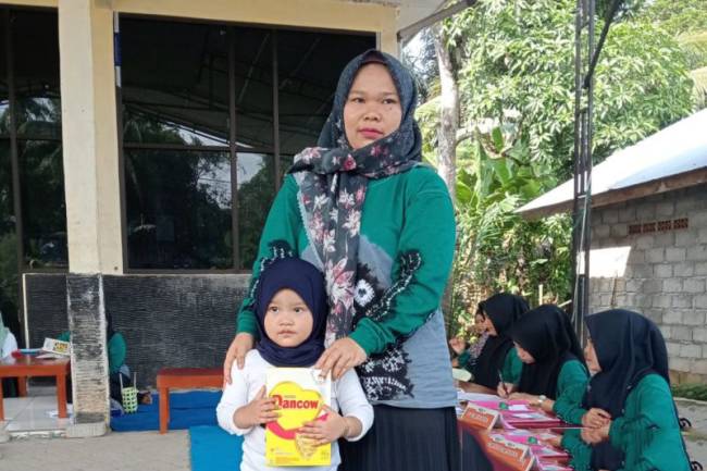 Seorang ibu mengantarkan sang anak memeriksakan kesehatan dan memberi susu tambahan di Desa Lok Batung, Kecamatan Paringin, Kabupaten Balangan, Kalimantan Selatan, Jumat (19/7/2024). [ANTARA/Herlina Lasmianti]