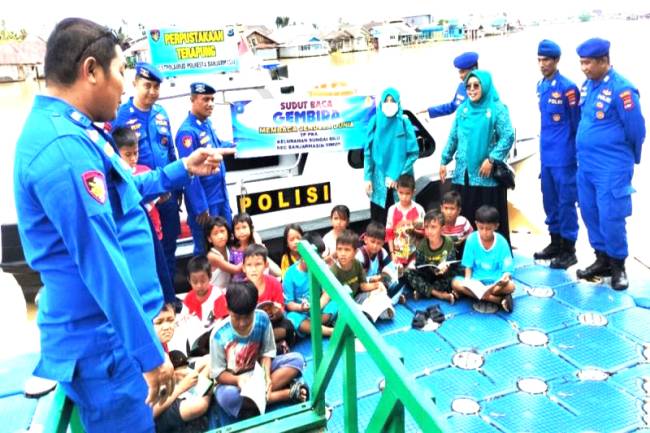 

Anggota Satpolairud Polresta Banjarmasin memberikan edukasi kepada anak pesisir sungai saat berada di kapal perpustakaan terapung. [ANTARA/Gunawan Wibisono]