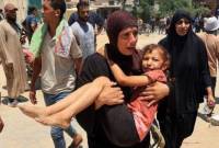 Seorang wanita Palestina membawa seorang anak yang terluka ke rumah sakit Nasser di Khan Yunis pada Sabtu (13/7/2024). [AFP/EYAD BABA]