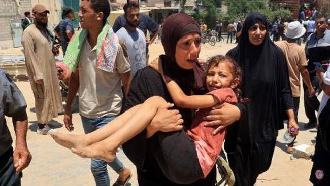 Seorang wanita Palestina membawa seorang anak yang terluka ke rumah sakit Nasser di Khan Yunis pada Sabtu (13/7/2024). [AFP/EYAD BABA]