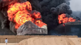 Seorang pria mengambil gambar api yang berkobar di tangki penyimpanan minyak sehari setelah serangan Israel di pelabuhan kota Hodeida yang dikuasai Huthi di Yaman pada Minggu (21/7/2024). [AFP via Getty Images]