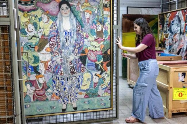 Nathalie Andrijasevic, asisten kurator di Museum Seni Tel Aviv, menangani lukisan karya pelukis Austria Gustav Klimt yang dipindahkan ke ruang bawah tanah di museum di Tel Aviv, Selasa (13/8/2024). (AFP)