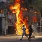 Pria berlari melewati pusat perbelanjaan yang dibakar oleh pengunjuk rasa selama unjuk rasa menentang Perdana Menteri Sheikh Hasina, 4 Agustus 2024. (AP Photo/Rajib Dhar)