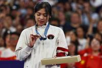 Gregoria Mariska Tunjung melihat ke arah medali perunggu yang didapatnya dalam seremoni penyerahan medali tunggal putri badminton Olimpiade 2024 Paris di Porte de La Chapelle Arena, Paris, Senin (5/8/2024). (REUTERS/Ann Wang)