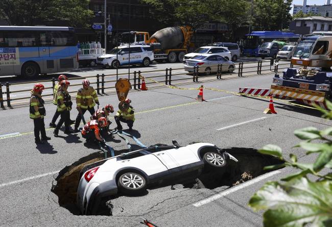 
Petugas pemadam kebakaran Korea Selatan bersiap mengangkat kendaraan yang jatuh ke lubang pembuangan di jalan di Seoul, Korea Selatan, Kamis (29/8/2024). (Seo Dae-yeon/Yonhap via AP)
