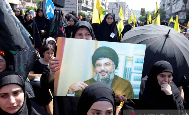 Seorang wanita Muslim Syiah membawa poster pemimpin Hisbulah Lebanon Sayyed Hassan Nasrallah saat prosesi religi menandai Asyura di daerah pinggiran Beirut, Lebanon. (REUTERS/Aziz Taher/aww/djo (REUTERS/AZIZ TAHER)