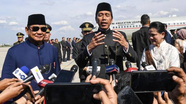 Presiden Prabowo Subianto (kiri) bersama Presiden ketujuh RI Joko Widodo (tengah) dan Istri Iriana Joko Widodo (kanan) menjawab pertanyaan wartawan saat akan memasuki pesawat Boeing 737 milik Angkatan Udara untuk bertolak ke Solo di Base Ops Lanud Halim Perdanakusuma, Jakarta, Minggu (20/10/2024). (ANTARA FOTO/Muhammad Adimaja)