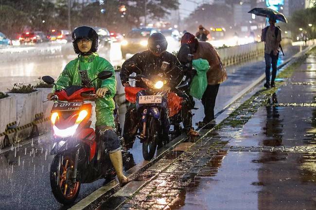 Foto Ilustrasi - Sejumlah pengendara motor berhenti untuk memakai jas hujan. (ANTARA FOTO/Idlan Dziqri Mahmudi)