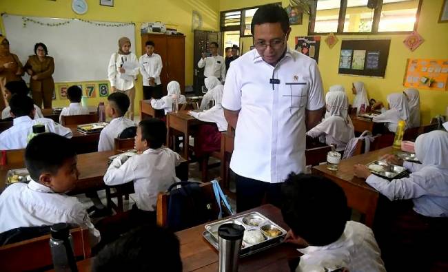Kepala Kantor Komunikasi Kepresidenan Hasan Nasbi (kedua kanan) berbincang dengan siswa saat meninjau pelaksanaan Program Makan Bergizi Gratis di SDN Kedung Badak 1, Tanah Sareal, Kota Bogor, Jawa Barat, Senin (6/1/2025). (ANTARA FOTO/Arif Firmansyah)
