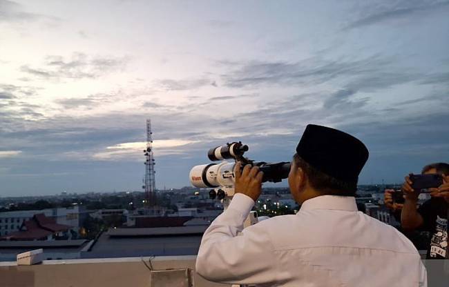 Kabid Urusan Agama Islam Kanwil Kemenag Kalsel H Muhammad Yamani saat melakukan peneropong untuk memantau hilal awal Dzulhijjah 1446 H atau 2025 M di atas Hotel Zurich Express Banjarmasin, Selasa (27/5/2025). (ANTARA/Sukarli)
