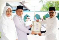 Kepala Kanwil Kemenag Kalsel H Muhammad Tambrin didampingi istri saat menyerahkan sertifikat atau SK izin operasional madrasah tahun 2025, di Banjarmasin, Senin (14/7/2025). (ANTARA/HO-Kemenag Kalsel)