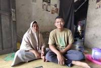 Mahasiswa UMPR penerima beasiswa dari Pemprov Kalteng Aswan (kanan) bersama sang ibu Imah berada di ruang tamu di rumahnya di Palangka Raya, Selasa (15/7/2025). (ANTARA/Rendhik Andika)
