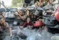 Seorang anak bersama pengungsi lainnya menunggu pembagian makanan gratis dari pusat distribusi makanan di Kota Gaza, Palestina (14/7/2025). (Xinhua/Rizek Abdeljawad)