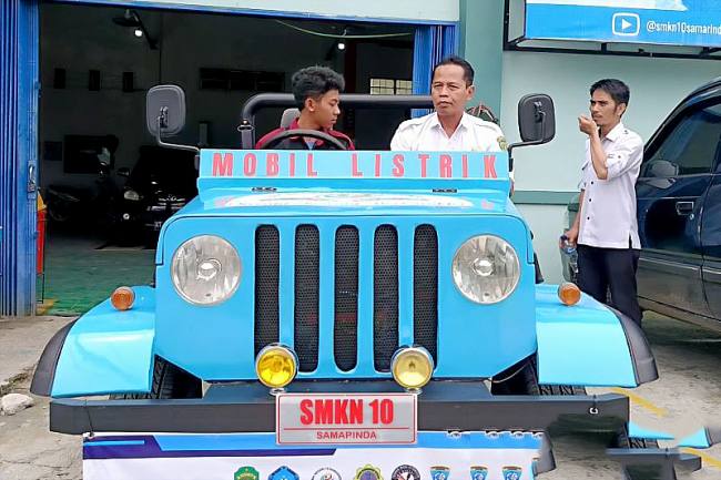 Kepala SMKN 10 Samarinda Maryono duduk di mobil listrik bersama siswanya. (ANTARA/A Rifandi)