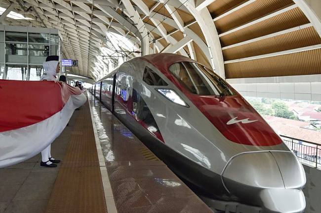 Petugas membentangkan bendera Merah Putih disamping Kereta Cepat Whoosh di Stasiun Kereta Cepat Halim, Jakarta Timur. (ANTARA FOTO/Fakhri Hermansyah)