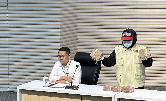 Pelaksana Tugas Deputi Penindakan dan Eksekusi Komisi Pemberantasan Korupsi Asep Guntur Rahayu (kiri) mempersilakan petugas untuk menampilkan barang bukti Rp500 juta terkait kasus dugaan suap pengurusan jabatan, proyek pekerjaan di Rumah Sakit Umum Daerah Dr Harjono Ponorogo, dan penerimaan lainnya atau gratifikasi di lingkungan Pemerintah Kabupaten Ponorogo, Jawa Timur, di Gedung Merah Putih KPK, Jakarta, Minggu (9/11/2025). (ANTARA/Rio Feisal)