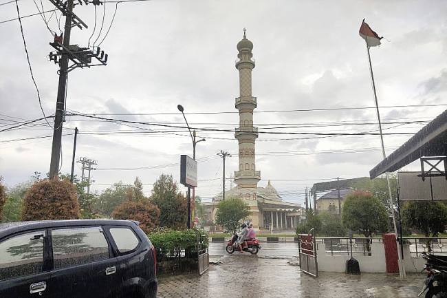 
Warga melintasi jalan raya di saat hujan mengguyur Kota Palangka Raya. (Foto: ANTARA/Rendhik Andika)