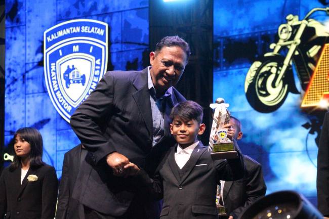 Penghargaan diserahkan Ketua IMI Kalsel Edy Sudarmadi kepada pembalap Motocross cilik asal Kandangan pada puncak gelaran Jambore IMI Kalsel, di Gedung Olahraga (GOR) Babussalam, Kota Banjarbaru, Sabtu (13/12/2025) malam. (SuarIndonesia/Ist)