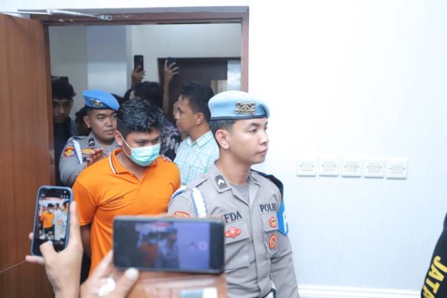 MS , mengenakan baju tahanan berwarna oranye, dengan kedua tangan terborgol, serta digiring petugas dari Provos dan lainnya yang mengawalnya dengan pengamanan ketat Jumat (26/12/2025. (SuarIndoneia/YI))