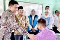 Wakil Menteri Dalam Negeri (Wamendagri) Akhmad Wiyagus (kiri) didampingi Wakil Gubernur Kalsel Hasnuryadi Sulaiman (kedua kiri) menyapa salah satu siswa saat meninjau penyaluran paket Makan Bergizi Gratis (MBG) di SMAN 1 Gambut, Kabupaten Banjar, Kalimantan Selatan, Rabu (3/12/2025). (Foto: ANTARA/Tumpal Andani A)