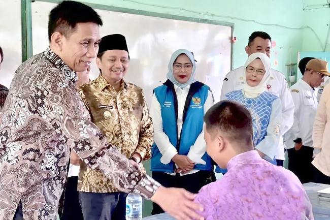 Wakil Menteri Dalam Negeri (Wamendagri) Akhmad Wiyagus (kiri) didampingi Wakil Gubernur Kalsel Hasnuryadi Sulaiman (kedua kiri) menyapa salah satu siswa saat meninjau penyaluran paket Makan Bergizi Gratis (MBG) di SMAN 1 Gambut, Kabupaten Banjar, Kalimantan Selatan, Rabu (3/12/2025). (Foto: ANTARA/Tumpal Andani A)