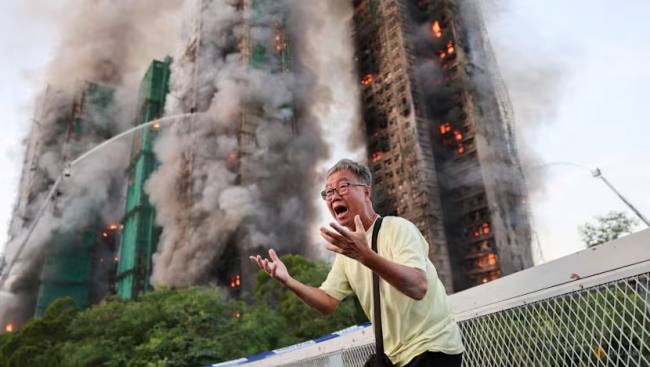 Warga Hong Kong histeris setelah mengetahui istrinya terjebak di salah satu kompleks apartemen Wang Fuk Court yang terbakar di Hong Kong. (Foto: Reuters/Tyrone Siu)