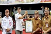 Bupati Kapuas Muhammad Wiyatno disaksikan Plt Sekda Kalteng Leonard S Amput menerima piagam rekor MURI melalui kegiatan bermain kecapi sambil bersenandung karungut di Kuala Kapuas, Senin (8/12/2025). (ANTARA/All Ikhwan)