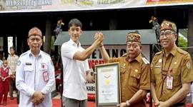 Bupati Kapuas Muhammad Wiyatno disaksikan Plt Sekda Kalteng Leonard S Amput menerima piagam rekor MURI melalui kegiatan bermain kecapi sambil bersenandung karungut di Kuala Kapuas, Senin (8/12/2025). (ANTARA/All Ikhwan)
