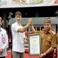 Bupati Kapuas Muhammad Wiyatno disaksikan Plt Sekda Kalteng Leonard S Amput menerima piagam rekor MURI melalui kegiatan bermain kecapi sambil bersenandung karungut di Kuala Kapuas, Senin (8/12/2025). (ANTARA/All Ikhwan)
