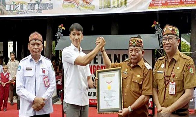 Bupati Kapuas Muhammad Wiyatno disaksikan Plt Sekda Kalteng Leonard S Amput menerima piagam rekor MURI melalui kegiatan bermain kecapi sambil bersenandung karungut di Kuala Kapuas, Senin (8/12/2025). (ANTARA/All Ikhwan)
