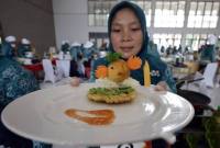 Seorang peserta memperlihatkan makanan berbahan baku ikan saat Lomba Cipta Menu Ikan di Kabupaten Kediri, Jawa Timur, Rabu (3/12/2025). Kegiatan yang diselenggarakan Pemkab Kediri tersebut sebagai upaya mendorong ibu rumah tangga menciptakan menu makanan sehat berbahan baku ikan dengan tampilan yang menarik agar anak gemar makan ikan guna mencegah stunting. (Antara Foto/Prasetia Fauzani)
